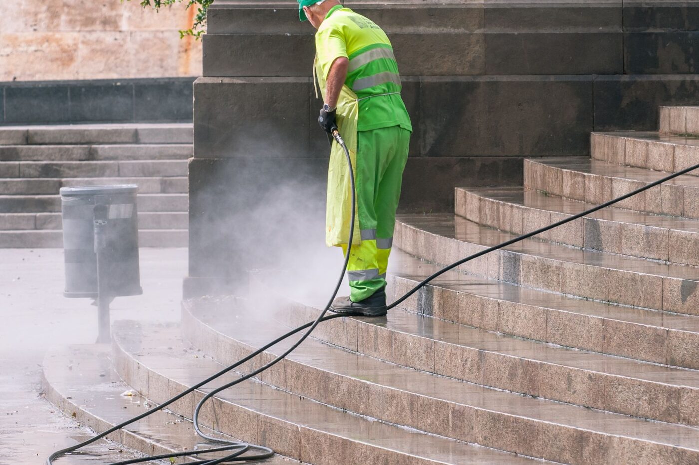 A technician pressure washing exterior stone steps, lifting dirt and grime