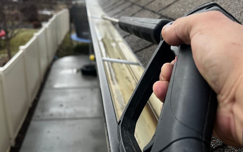 Cleaning a gutter with a pressure washer